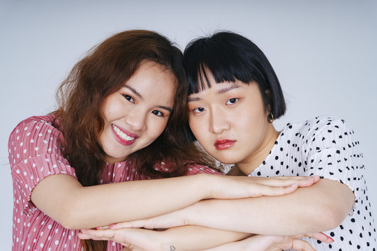 两位穿着白色和粉色连衣裙的年轻亚洲女性做着奇怪事情的特写肖像。