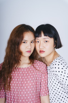 两位身穿粉色和白色帕尔卡多特服装的年轻亚洲女性的特写肖像。
