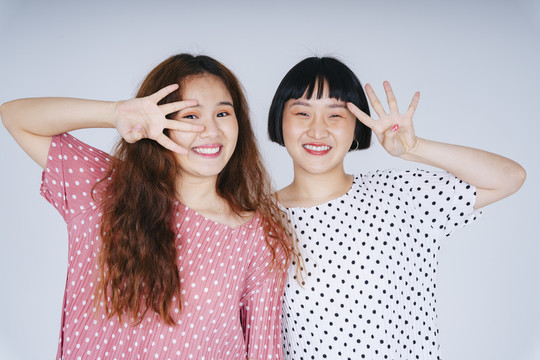 在白色背景上，两位年轻的亚洲女性穿着礼服，表达惊讶和兴奋。