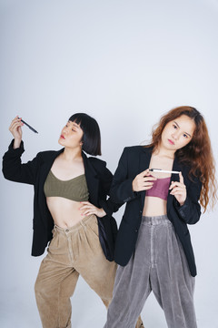 两位穿着黑色夹克套装、白色背景上有一支笔的年轻亚洲商业女性的肖像。