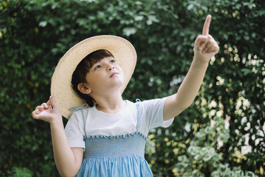 身穿蓝白色连衣裙、戴着帽子的小女孩的画像指向天空。