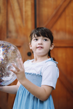 在谷仓里玩塑料球的小女孩的肖像。