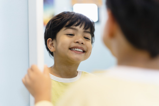 快乐的男孩在镜子前自信地微笑的肖像。