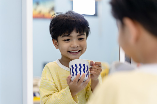 小男孩在镜子前用鲜奶吃早餐。