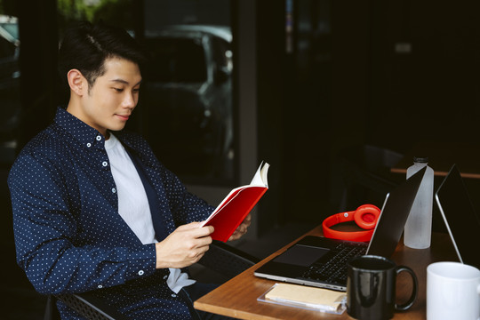 年轻的亚洲商人在回去工作前读一本书。