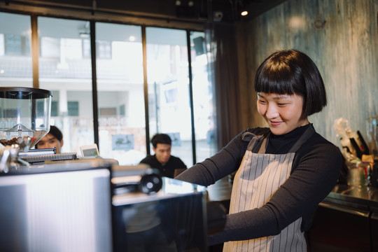 在自助餐厅为顾客煮咖啡的亚洲短发女咖啡师。
