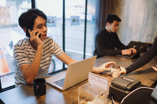 在自助餐厅使用笔记本电脑和智能手机的自由职业者。