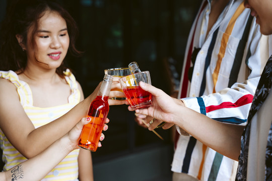 亚洲人和朋友在聚会上用酒杯和酒瓶敬酒。