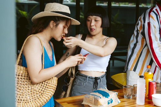 两位年轻的旅游妇女在夏季聚会上吃零食。