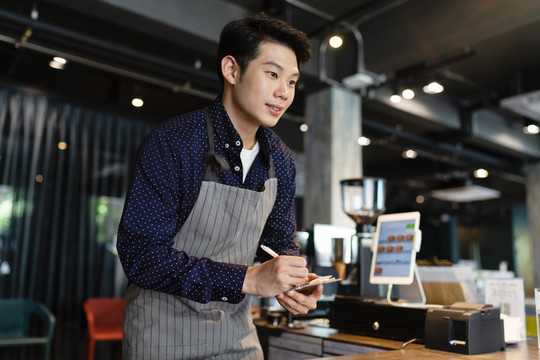 亚洲男咖啡师在咖啡馆向顾客点菜。
