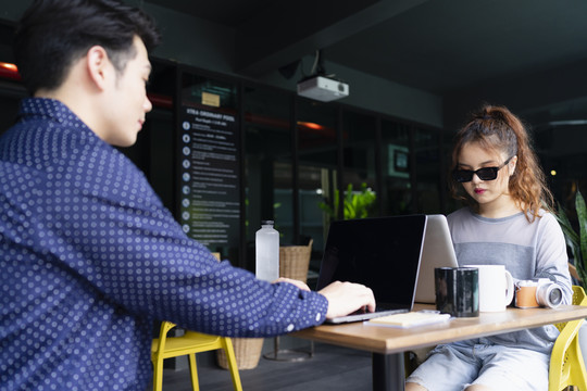 亚洲夫妇在户外咖啡馆约会和工作。