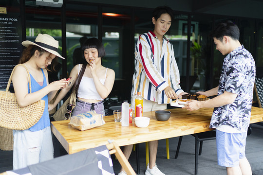 一群亚洲游客在酒店休息室的夏季派对上享用小吃。