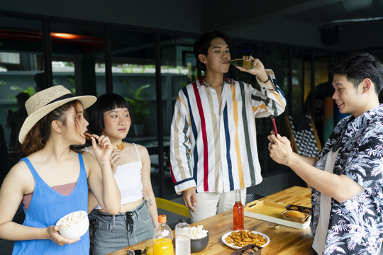 一群亚洲游客在酒店休息室的夏季派对上享用小吃。