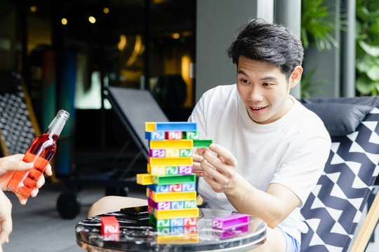 穿着白衬衫的亚洲男子在派对上玩jenga block。