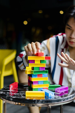 年轻人在聚会上和朋友玩五颜六色的jenga。
