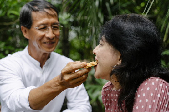 一对亚洲老夫妇在自家后院一起吃早餐。