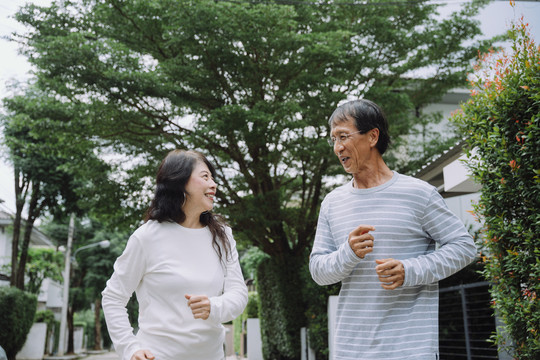 快乐的亚洲老年夫妇在公园户外慢跑锻炼。