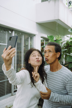 快乐的亚洲老年夫妇用智能手机自拍。老年人社交媒体概念。