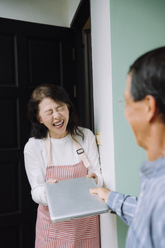 快乐的亚洲前妻在上班前把笔记本电脑送给丈夫。