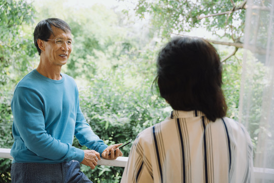 亚洲老年夫妇在阳台上相互交谈。