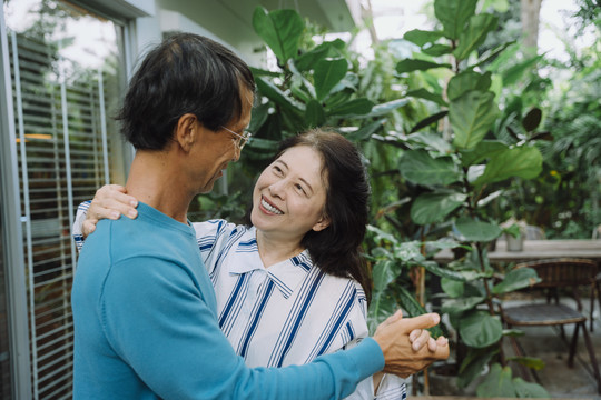 亚洲老年夫妇在后院拥抱跳舞。