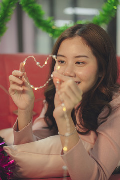年轻的亚洲女子玩着心形圣诞灯。