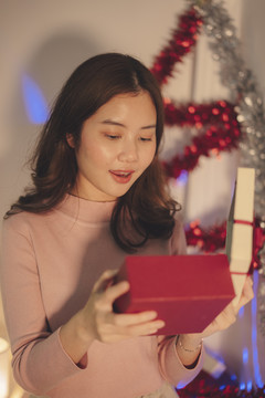 美丽的亚洲年轻女子黑发在派对上打开圣诞礼品盒。