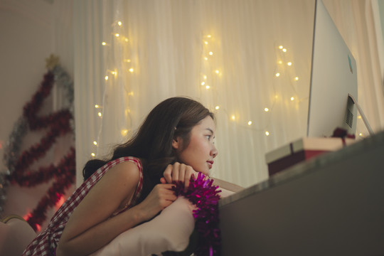 侧视图-孤独的亚洲女孩在网上和朋友在电脑上庆祝圣诞派对。