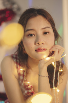 美丽的亚洲年轻女子黑头发在家里玩圣诞灯。