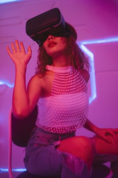 模特年轻的卷发女人戴着虚拟现实虚拟现实的眼镜在未来的房间里。
