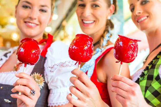 朋友们穿着民族服装一起参观巴伐利亚博览会，吃着苹果糖