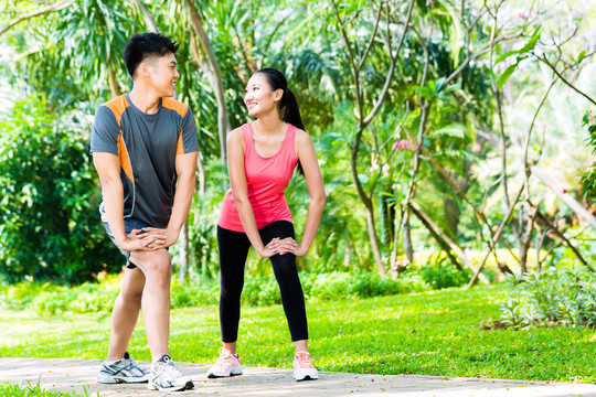 亚洲华人男子和女子在公园伸展肌肉进行运动健身