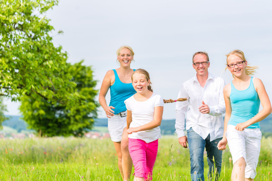 夏天，家人、父母和女儿在田野或草坪上奔跑