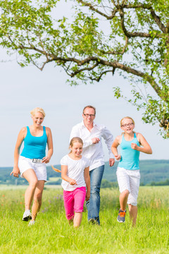 夏天，家人、父母和女儿在田野或草坪上奔跑