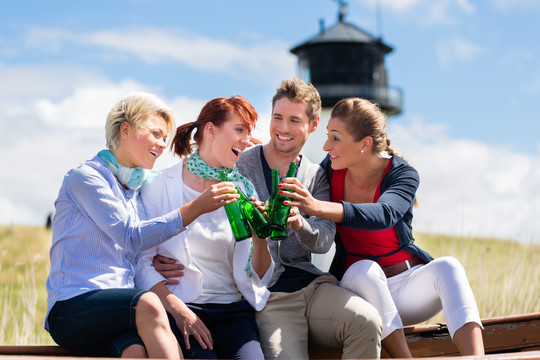 朋友们喝着瓶装啤酒在德国北海海滩度假