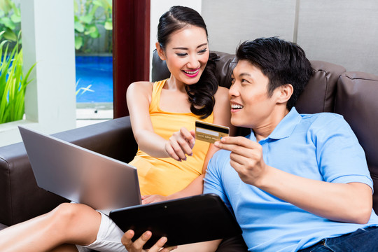 亚洲夫妇使用笔记本电脑和信用卡在网上购物