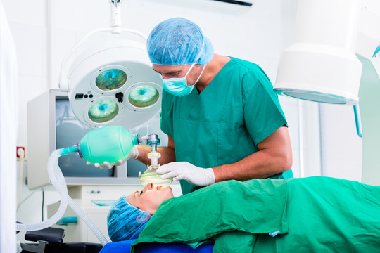 医生外科医生和病人在手术室使用带面罩的麻醉剂