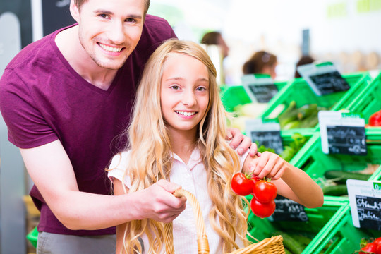 父亲和女儿在有机超市购物时挑选蔬菜