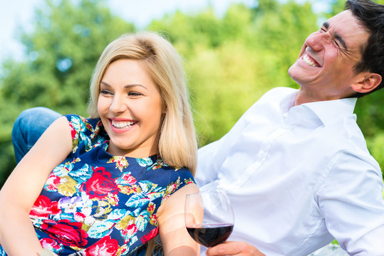野餐时，一对夫妇在公园草地上喝红酒