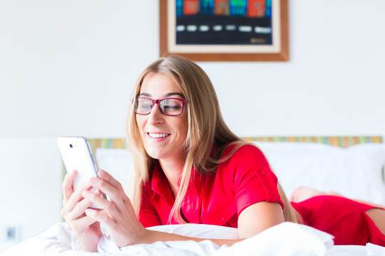 女人在床上用智能手机看邮件