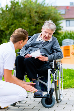 夏季，护士推着轮椅上的老年妇女穿过花园