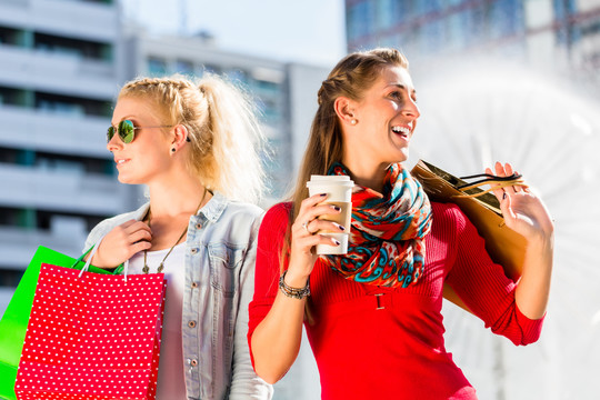女人们在城里购物，手里拿着袋子，手里拿着咖啡和袋子