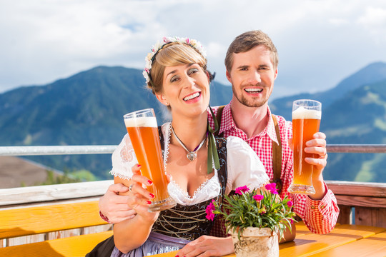 情侣们在山间小屋里喝着小麦啤酒，背景是阿尔卑斯山的风景