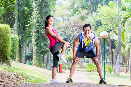 一对亚洲男女在热带公园进行体操伸展运动健身