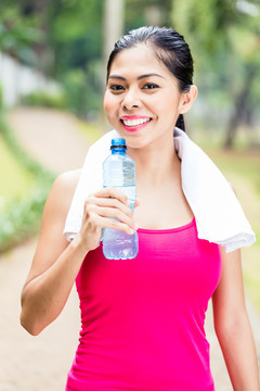 正在接受成功运动训练的亚洲女子手拿水瓶竖起大拇指