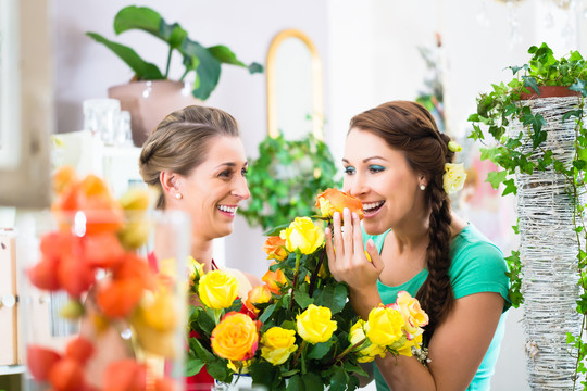 在花店里欣赏玫瑰花的女人们嗅着玫瑰花