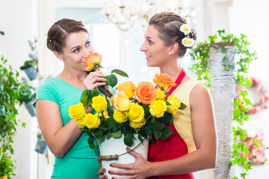 在花店里欣赏玫瑰花的女人们嗅着玫瑰花