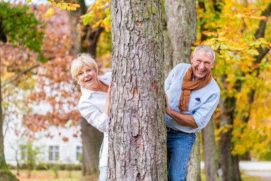 这对老夫妇，一对年长的男人和女人，在秋天的树上玩捉迷藏，互相调情