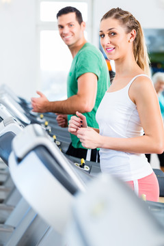 健身馆跑步机上的情侣为运动而跑步