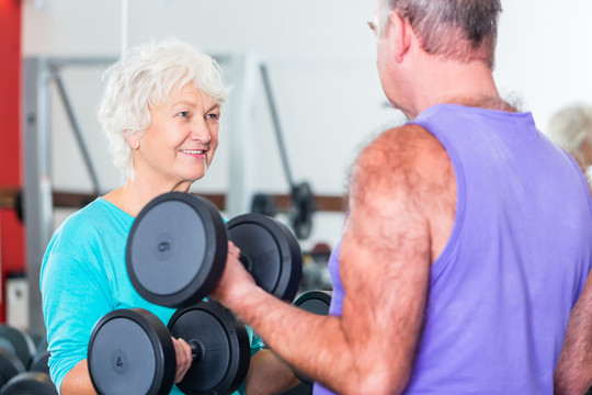 老年夫妇，男男女女，在健身房举重哑铃进行健身锻炼